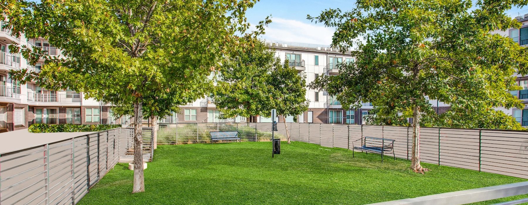 a fenced in area with trees and buildings in the background